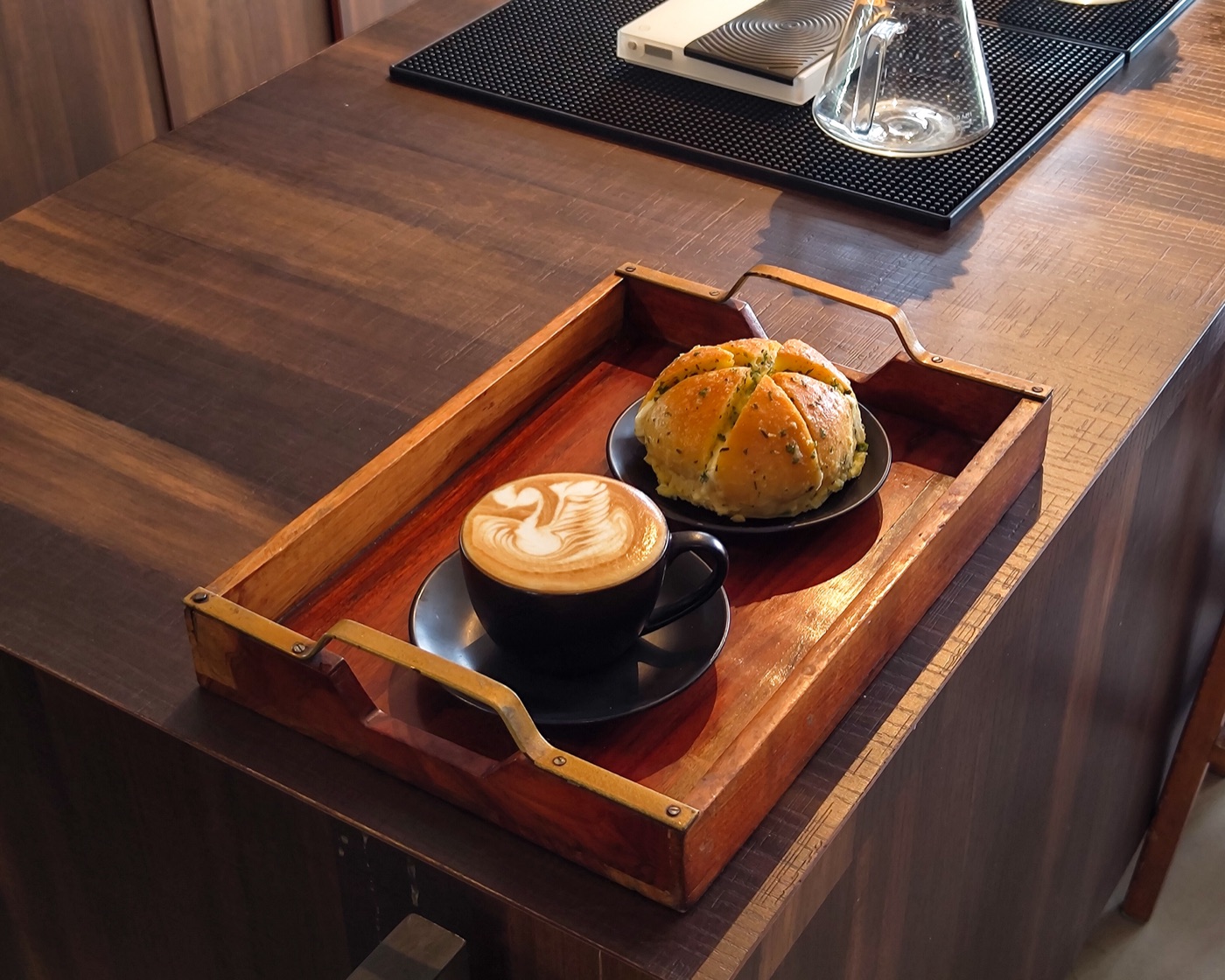 A garlic cheese bun and a latte served on a wooden tray at Autumn Brew