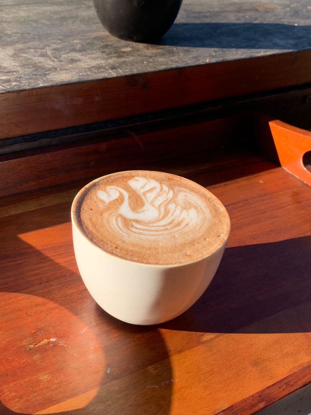 A flat white with swan latte art in a cream cup, in morning light at Autumn Brew