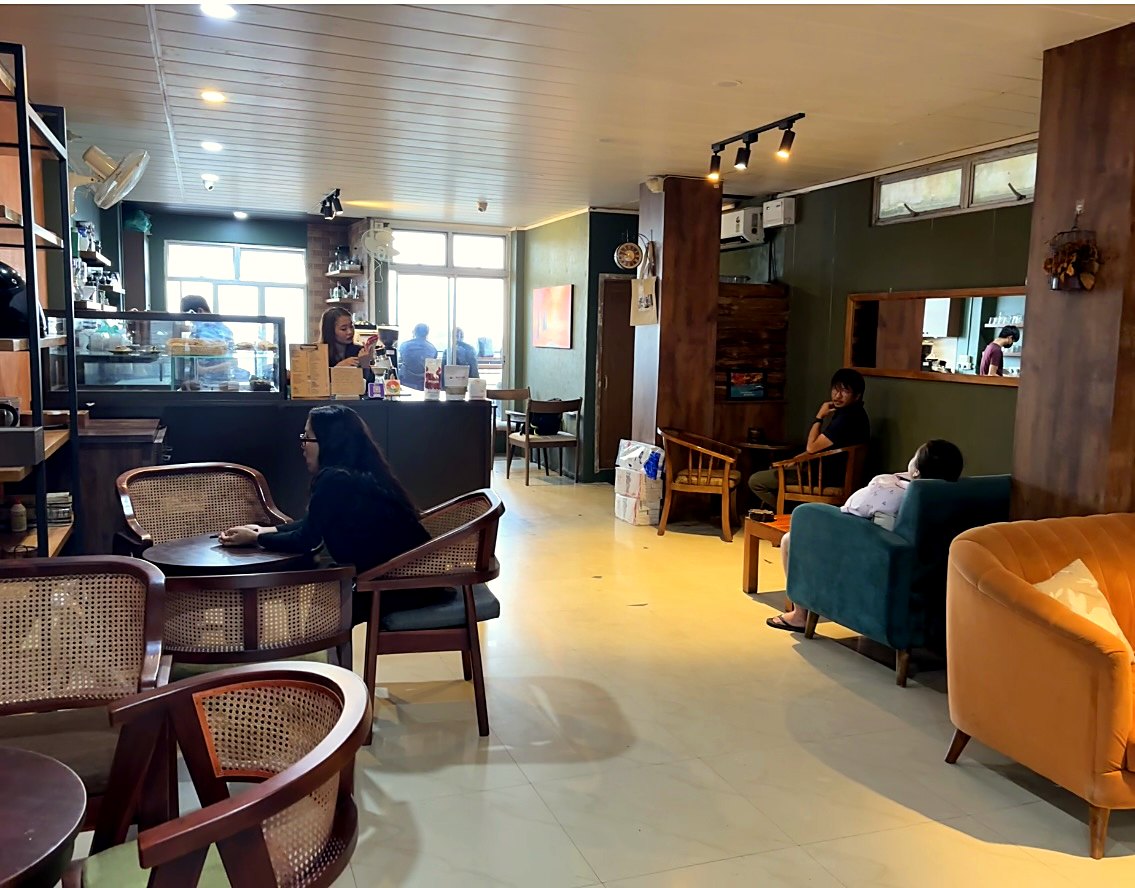 Guests at the cane chairs and velvet sofas inside Autumn Brew, the counter behind